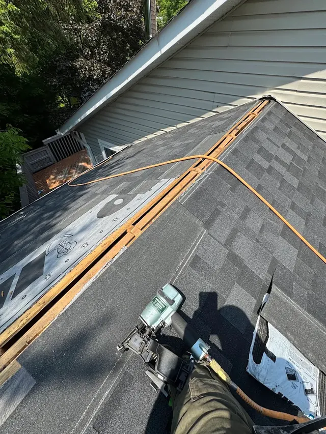 Roofer installing shingles mid-repair